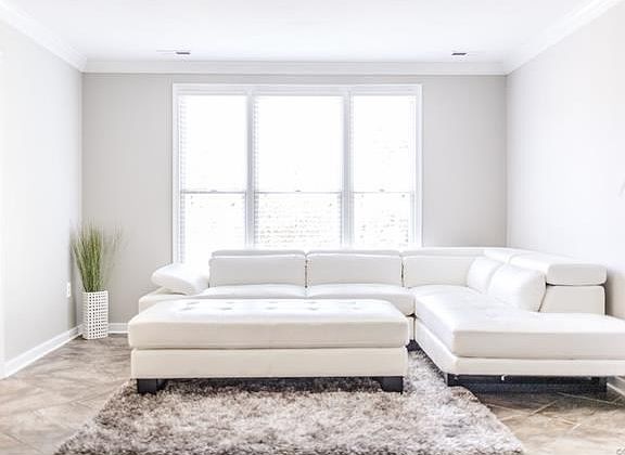 Nicely appointed living room with triple window, crown molding and neutral paint.