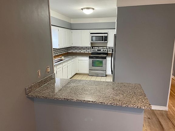 Spacious kitchen boasts brand-new granite countertops, stainless fridge and stove, over-range microwave, and abundant storage