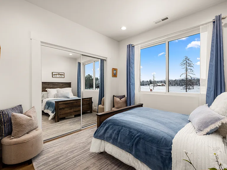 One of the additional bedroom suites featuring mirrored closet doors, beautiful mountain views, and a private en-suite bath, creating a peaceful and inviting retreat.