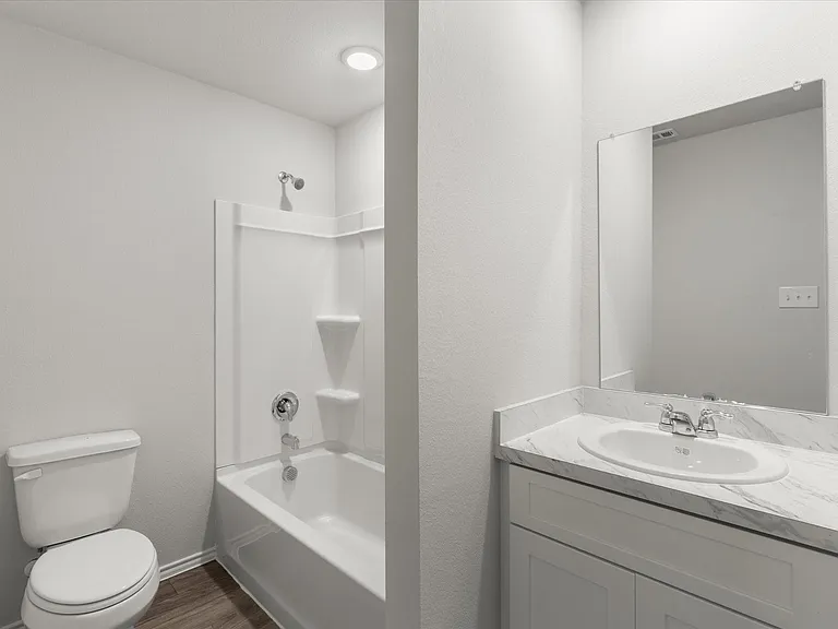 Full bathroom featuring a white tub/shower combination, white toilet, and a vanity with a white countertop and oval sink