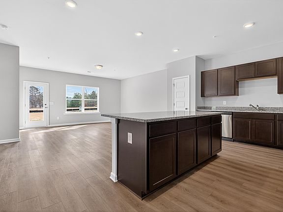 Kitchen featuring dark wood finish cabinets, a center island, light wood-style flooring, recessed l