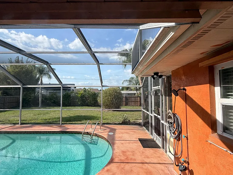 Screened-in pool patio with expansive deck space, ideal for outdoor lounging and entertaining with backyard views.