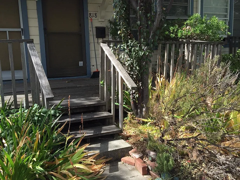Front door with wood deck and landscaping