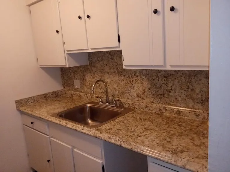 Right side of kitchen showing newer counter top, sink and ample cabinets