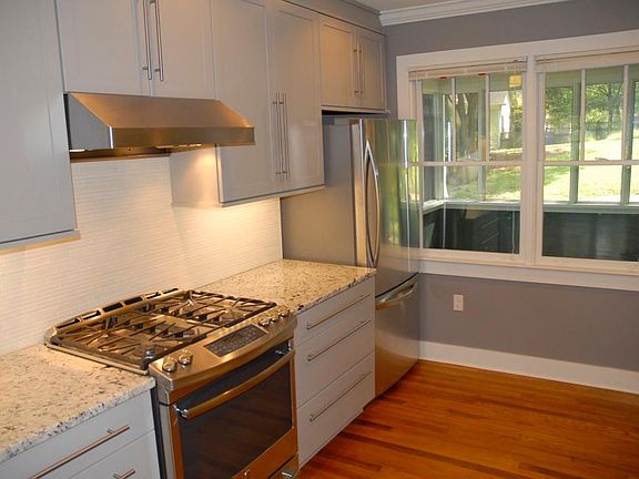 Gourmet gas stove and fridge showing screen porch beyond.