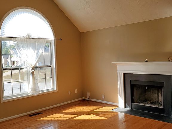 Living room with fireplace, picture window and ceiling fan.