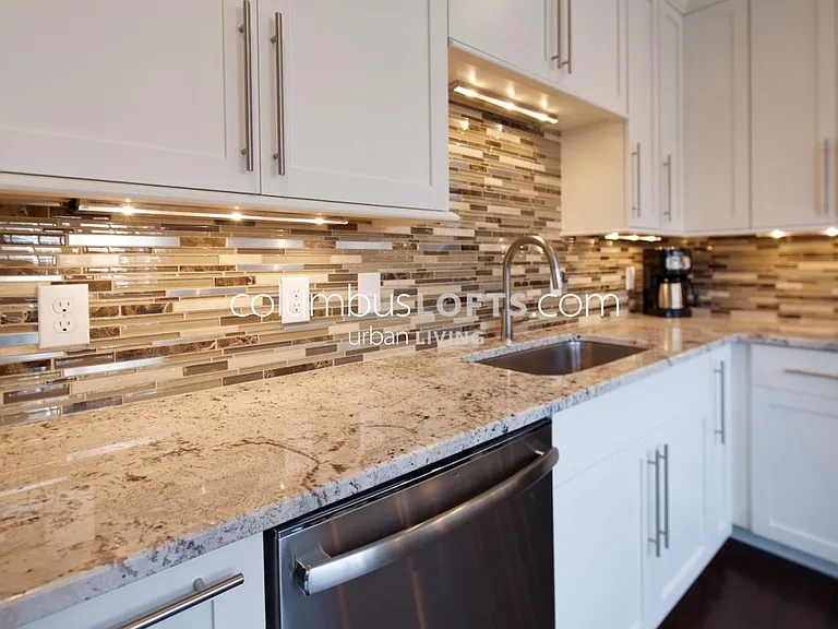 kitchen detail: white granite tops, glass tile backsplash, under-cabinet lighting, high-end appliances