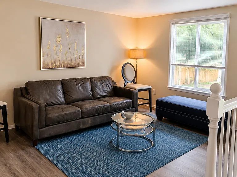Comfortable living area with a leather sofa, accent seating, and a coffee table, plus a large window and durable flooring.