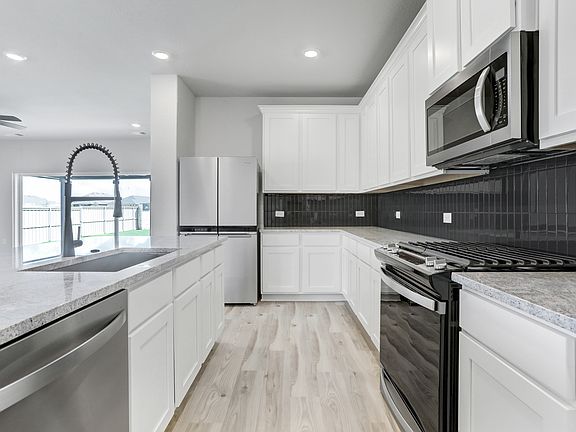 Upgraded kitchen showcasing white cabinets with crown molding and granite countertops.