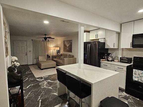 The kitchen features built-in Whirlpool appliances, including a refrigerator, dishwasher, stove, microwave, and garbage disposal. A deep farm-style sink adds both function and charm to the space.