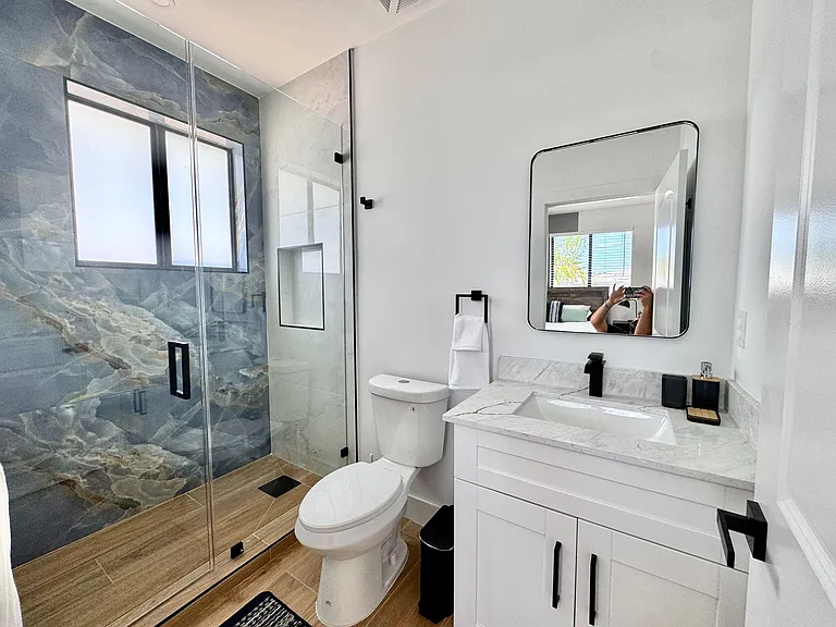 Updated bath with glass-enclosed shower, tile surround, and a wide vanity with ample counter space.