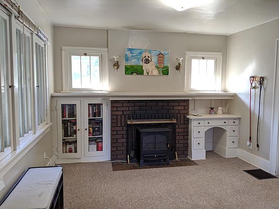 Living room (south end) with electric insert fireplace, built-in desk and shelves. Lots of windows to front porch.