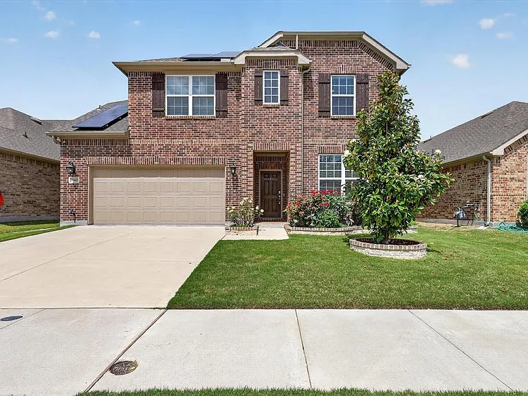 Two-story brick exterior featuring a two-car garage, concrete driveway, and front lawn with mature landscaping