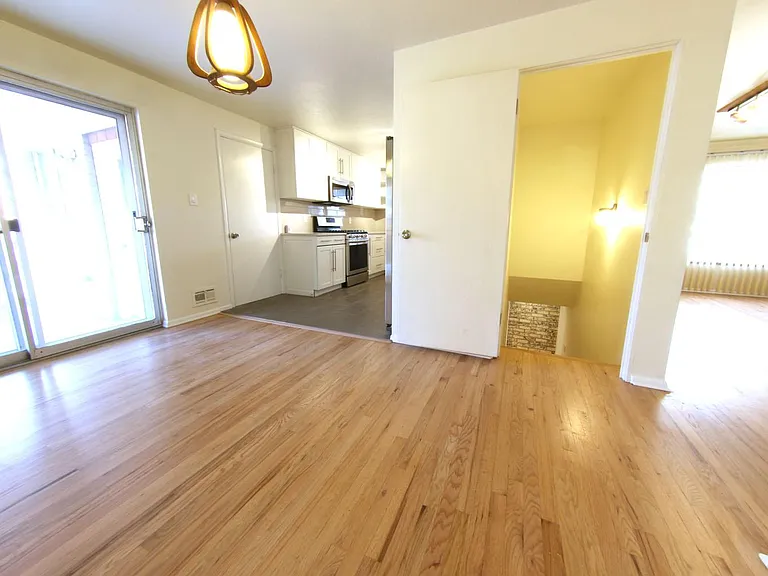 View of Dining Area, kitchen, and patio door to covered porch- Note Stairs to basement in center of photo.