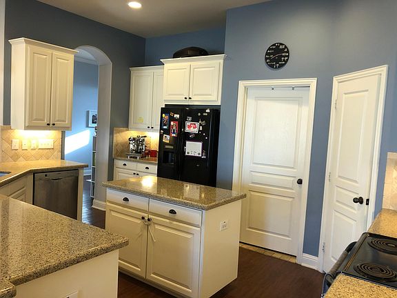 View of kitchen from breakfast/dinning area. Pantry to far right past stove, laundry room adjacent