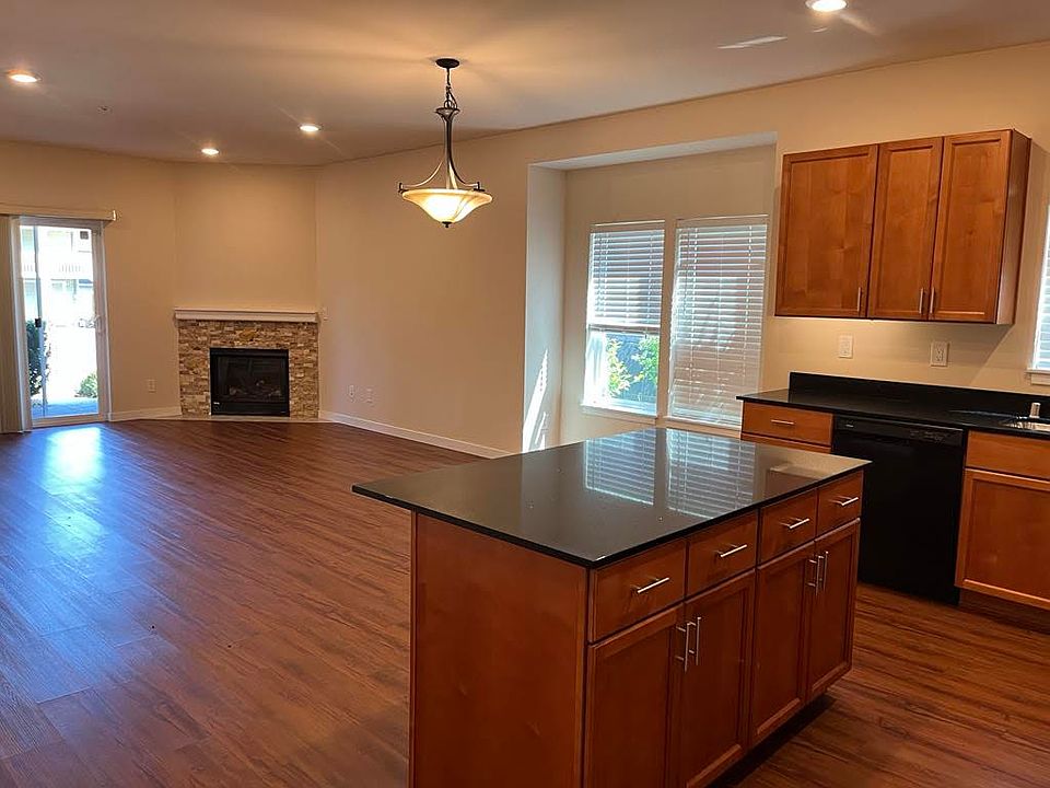 Bright open-concept kitchen and living area featuring durable LVP flooring, center island, ample cabinet space, cozy fireplace, and sliding glass doors that fill the space with natural light.