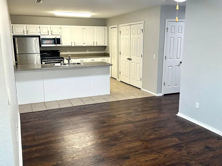 Living room into dining and kitchen area. Bright LED lights throughout the unit.