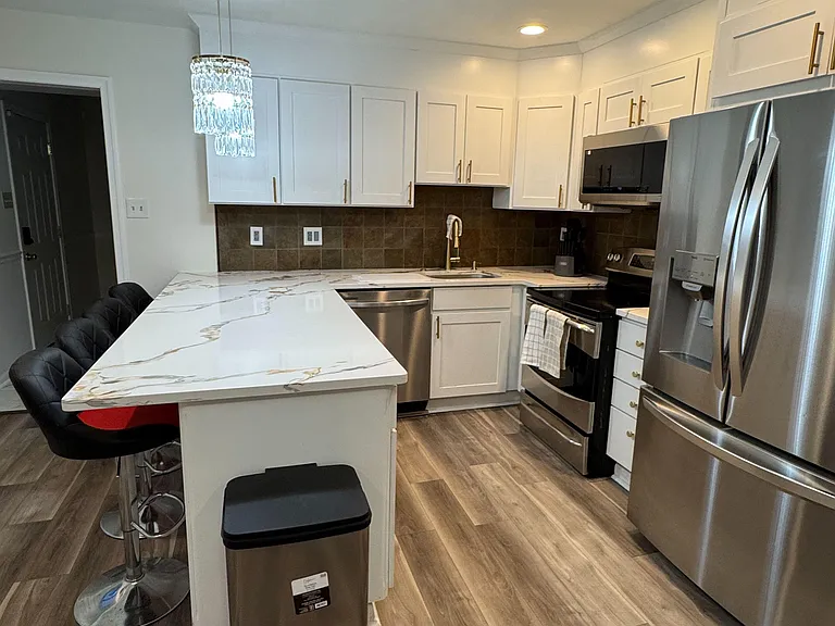 Updated kitchen with white cabinetry, stone-look island seating, and stainless steel appliances for everyday convenience.