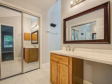Spacious vanity area with mirrored closet doors and plenty of storage.