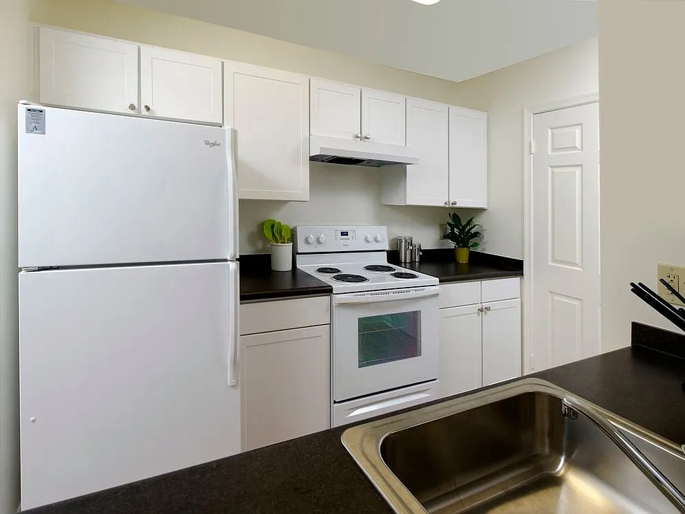 Kitchen with white appliances, white cabinetry and black countertops - eaves Fairfax City