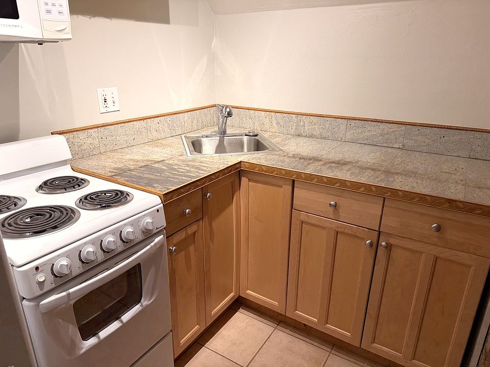 Granite countertop, beautiful wood cabinetry, and tiled flooring.
