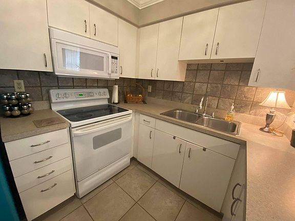 Fully Stocked Kitchen with Breakfast Bar, Full Sized Refrigerator, and Microwave.