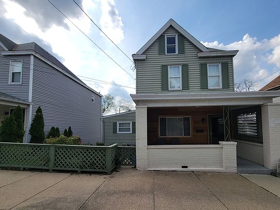 The front view highlights the spacious double lot and landscaped front yard, with an EV charging station positioned on the left side of the property.