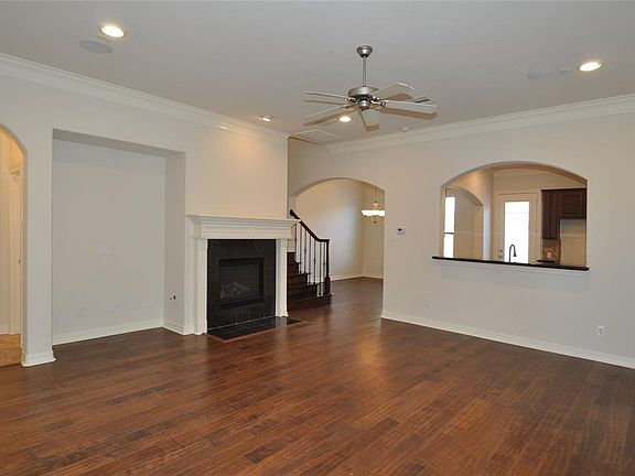 Large living area with wood flooring, recessed lighting, gas log fire place, high ceiling and crown molding.