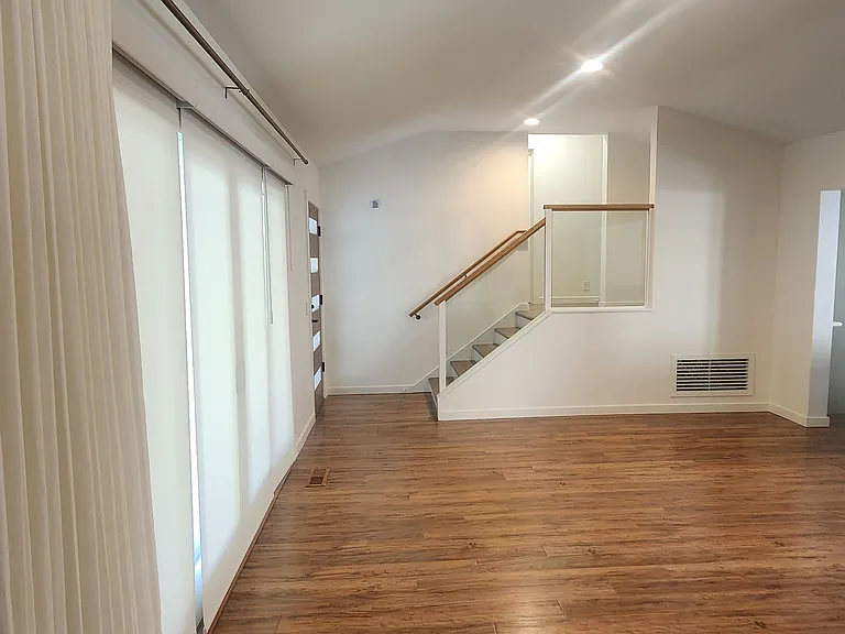 The living room is west-facing towards the entrance and has split-level stairs to the upper bedrooms and bathroom.