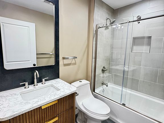 Primary bathroom with modern tile and glass enclosed tub shower
