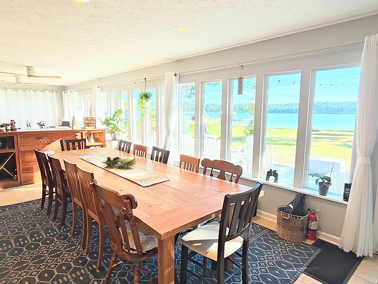 Dining area with view of the water, bar, and a living area/office area behind it.