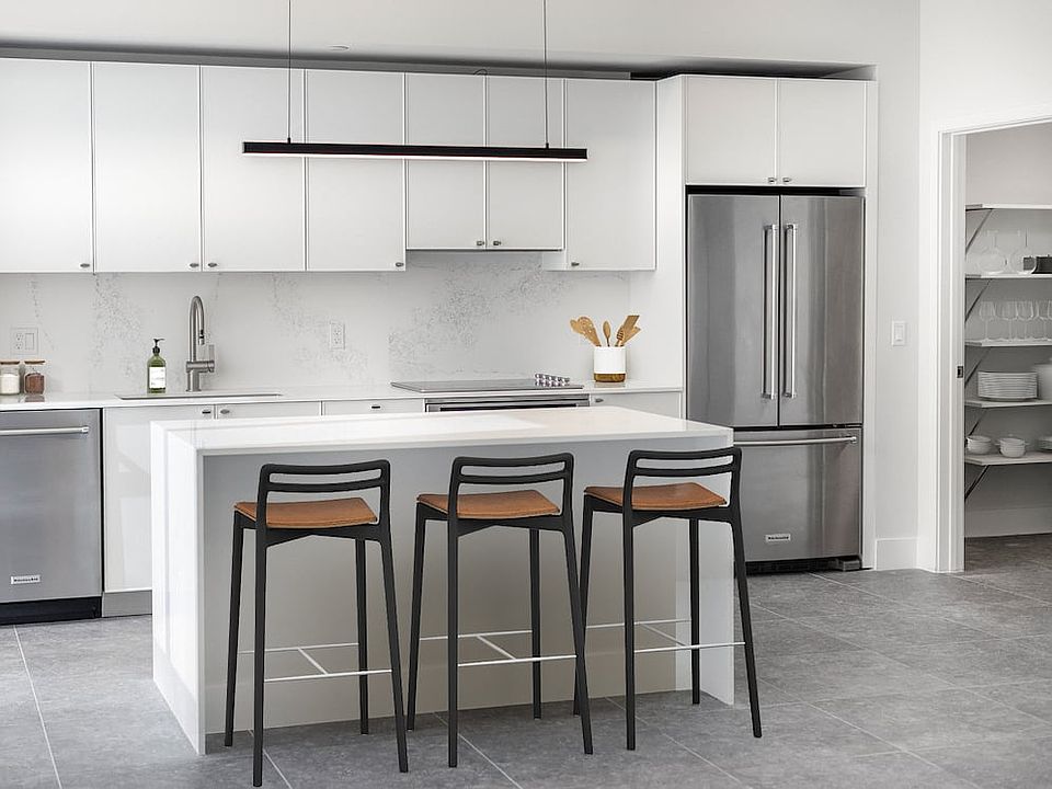 Signature Collection Townhome kitchen with white cabinetry, white marbled quartz countertop and backsplash, wine fridge, and upgraded stainless steel appliances