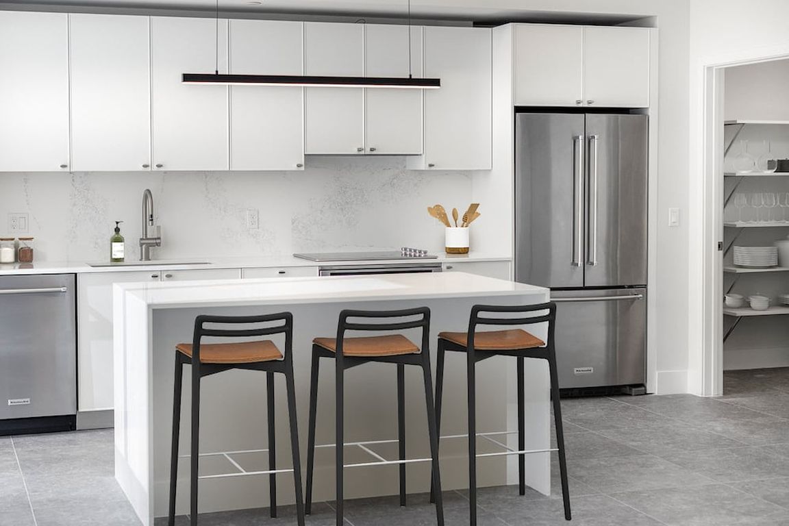 Signature Collection Townhome kitchen with white cabinetry, white marbled quartz countertop and backsplash, wine fridge, and upgraded stainless steel appliances