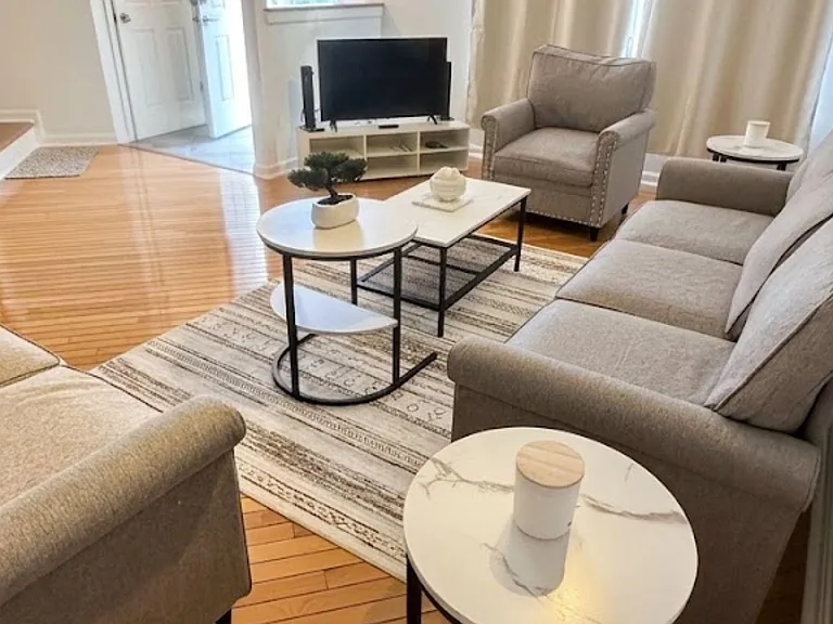 Living room with hardwood floors, seating for multiple, and a TV areaideal for relaxing or shared downtime.