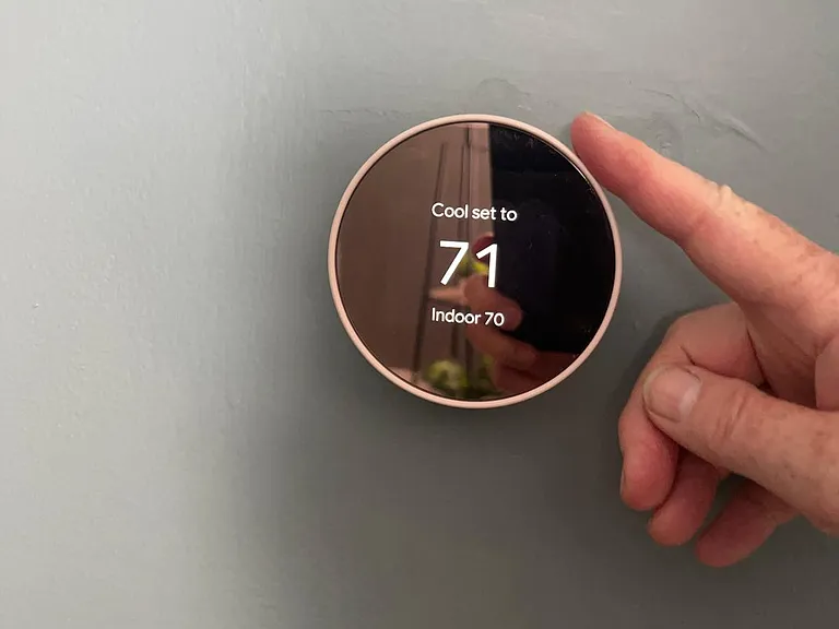 This thermostat in the living room controls the temperature of the entire house, both heat and air. To change the temperature, gently touch the outside of the dial and turn it up or down with one finger.