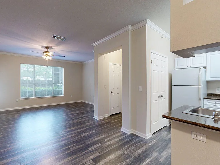 Apartment Kitchen with Stainless Steel Appliances, Dining and Living Room with Wood-Style Flooring.