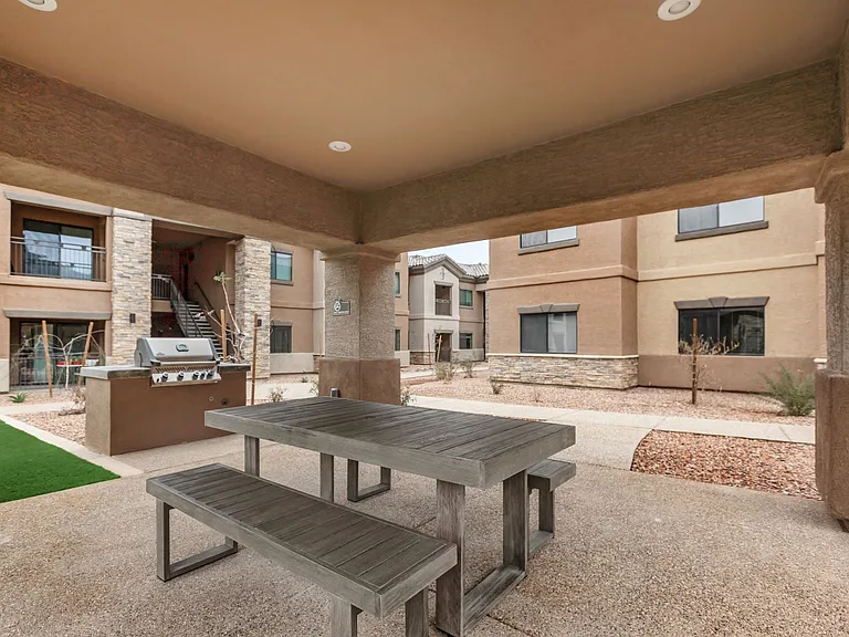 Outdoor covered patio with gas grill and picnic table