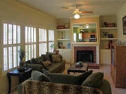 Family room looks out onto backyard through lots of windows with pretty shutters.