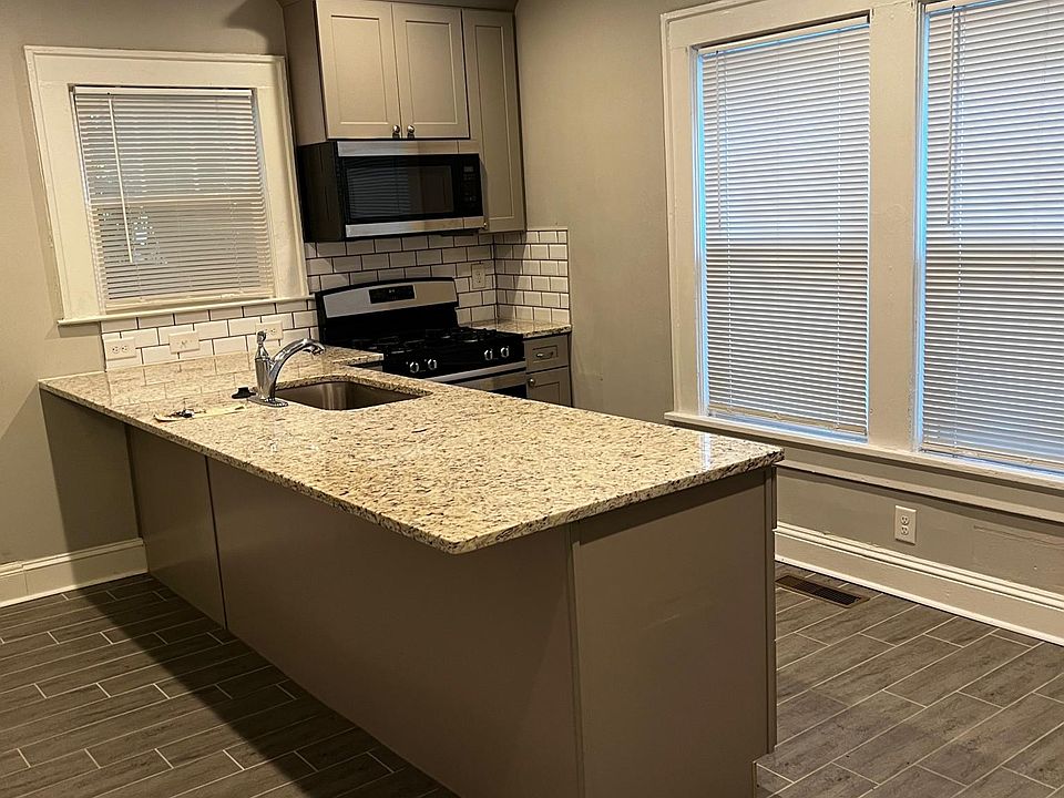 Kitchen peninsula with granite counters and subway tile backsplash.