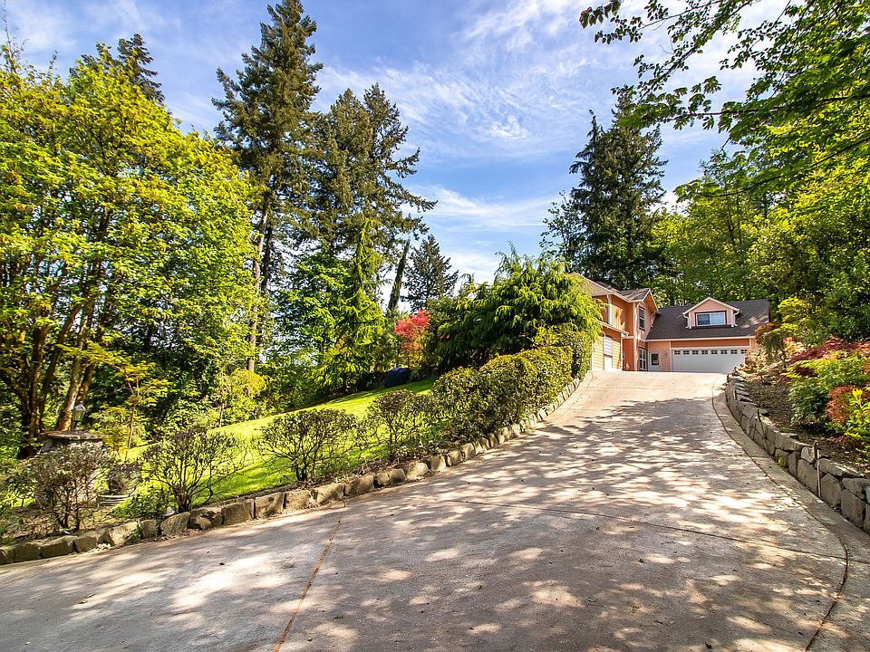 A long paved driveway leads up to the house, beautifully landscaped.