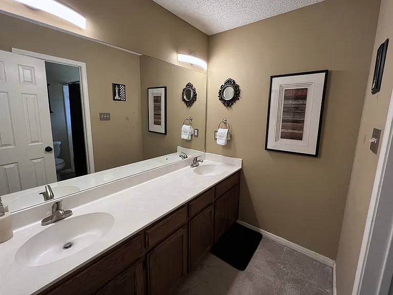 One of three bathrooms, this bathroom features double sinks with ample storage, LED lighting, a shower room