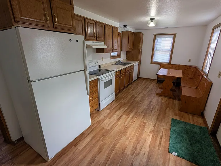 Eat-in kitchen with ample wood cabinetry, full-size appliances, and space for a dining nook beside the windows.