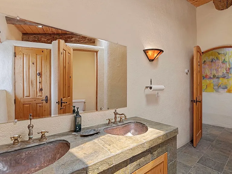 Two private toilet stalls and natural stone counter top with copper sinks