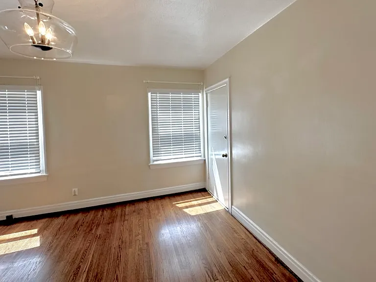 BEDROOM WITH DOOR TO REAR OF BUILDING AND GARAGES