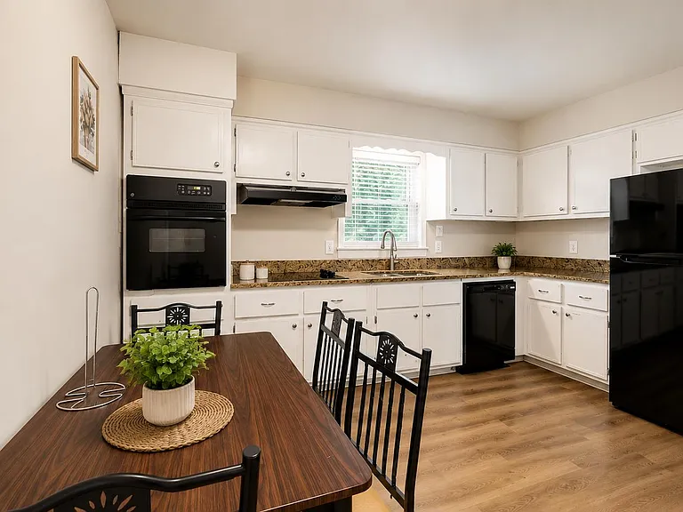 Spacious eat-in kitchen with ample white cabinetry, granite-look counters, and a full appliance package for easy meal prep.