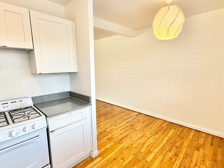 Modern apartment kitchen with sleek white cabinetry and stylish wood floors, perfect for urban living.