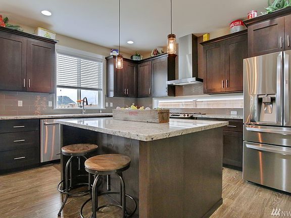 Gourmet kitchen features oversized island, granite counter tops, stainless steel appliances, tile backsplash & walk in pantry.