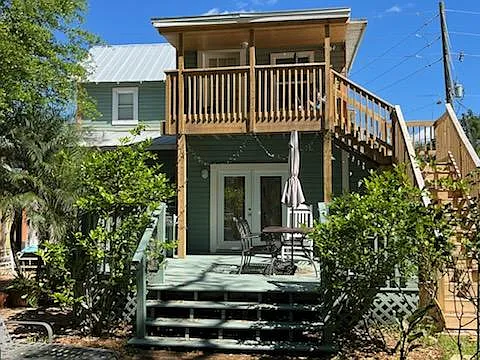 View of house from backyard showing external stairway to upstairs covered porch.