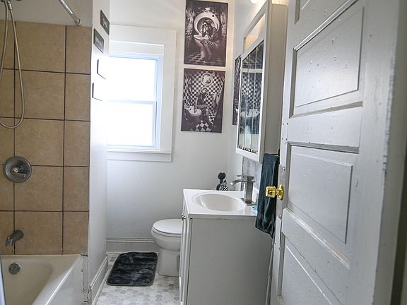 Compact full bathroom with a tub/shower combo, updated vanity, and a window for natural light and ventilation.