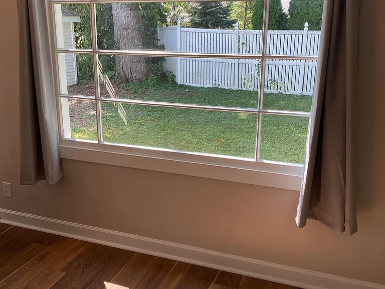Large window in dining/family room area faces open space, no direct neighbors allowing curtains to stay open